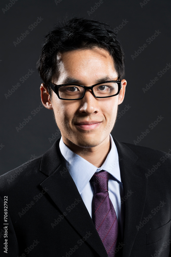 Stylish Chinese business man. In front of dark background