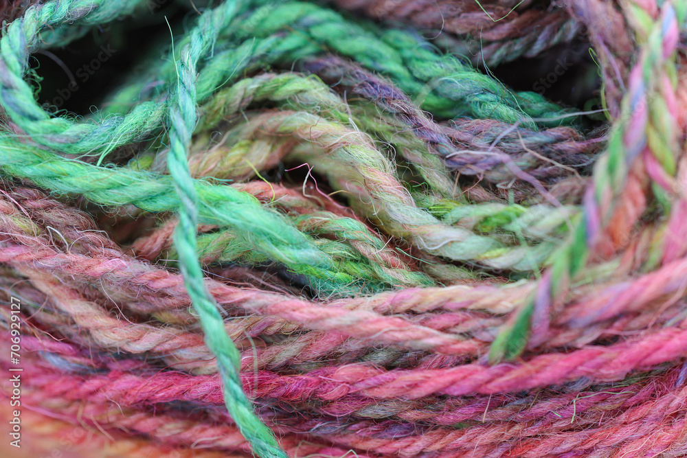 Closeup detail of colourful ball of wool, skeins of organic natural handspun and handdyed merino sheep wool, silk, linnen mix yarn fleece, spun on a traditional spinning wheel