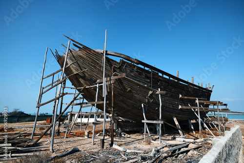 Construction of a wooden ship. Shipyard of traditional Dhow wooden boat on Iranian Qeshm Island. Tradition Lenj Fishing Boat in Qeshm Island in Southern Iran. Old wooden stealth smuggler's ship