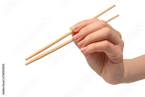 Female hand holding wooden sushi chopsticks isolated on white background.