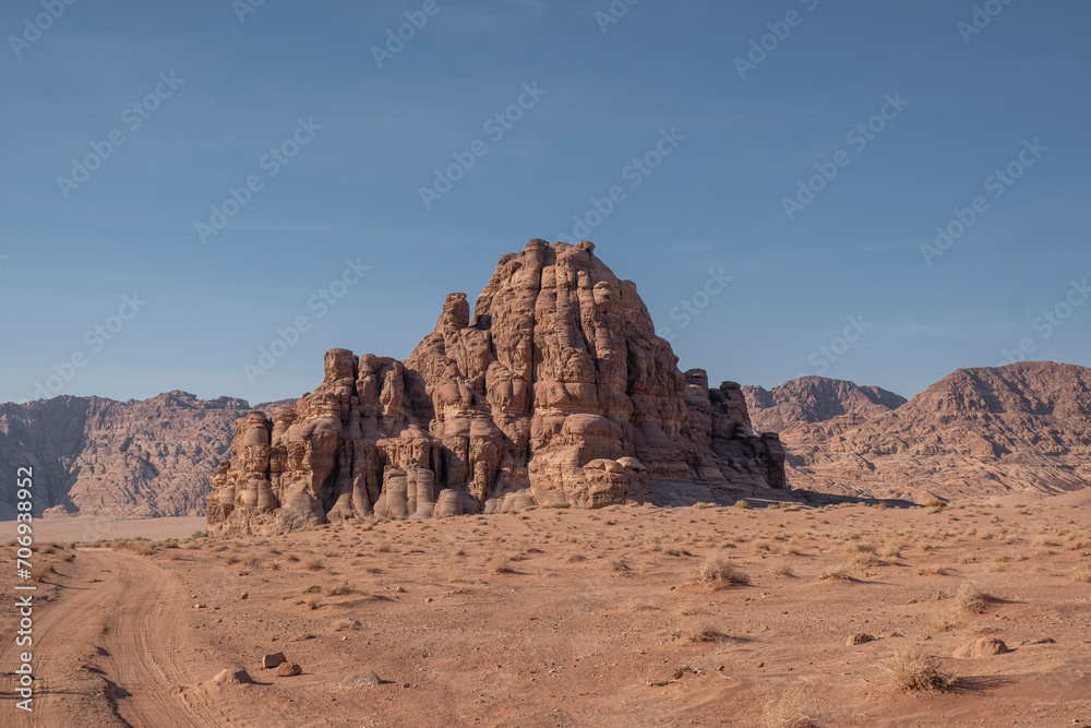 A dirt road stretching through the arid and vast Wadi Rum desert in Jordan.