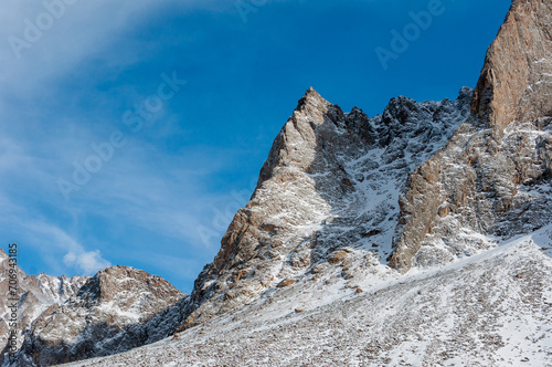 A lone jagged mountain peak  covered with a fresh layer of snow  stands under the vast blue sky
