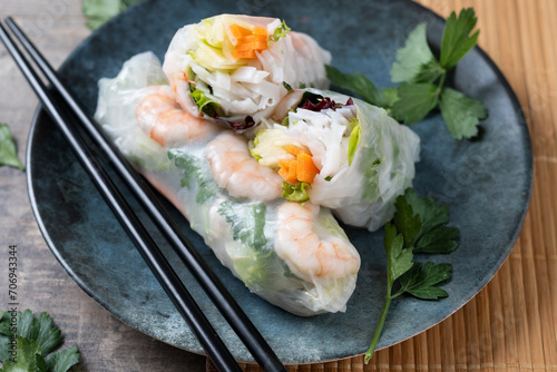 Vietnamese spring rolls with vegetables, rice noodles and prawns on wooden table. Close up
