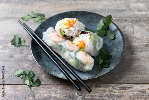 Vietnamese spring rolls with vegetables, rice noodles and prawns on wooden table