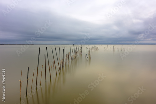 Fishing poles and nets over water with a long exposure sky