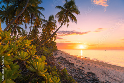 Tropical beach with coconut palms with sunrise or sunset and sea