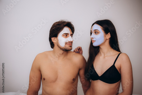 Husband and wife are lying on couch home and doing restoring face masks portrait. Healthy facial skin care at home help concept