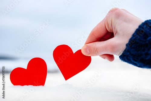 Woman's hand holding red heart on winter background. Love is coming concept.