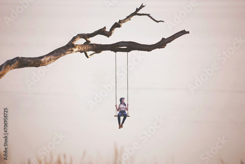 surreal woman swings on a swing hanging from a branch, concept of freedom and precariousness photo