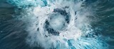 View from above of white foamy whirlpool, blue water, green