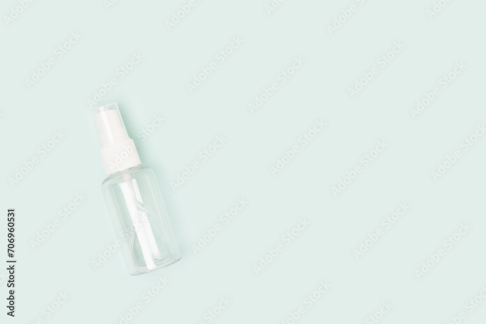 One empty transparent spray bottle on a blue background. Place for text. One empty transparent spray bottle on a blue background. Place for text.