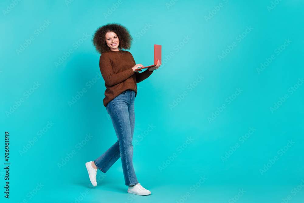 Full length photo of lovely lady walk hold netbook smm manager dressed stylish brown garment isolated on aquamarine color background Full length photo of lovely lady walk hold netbook smm manager dressed stylish brown garment isolated on aquamarine color background
