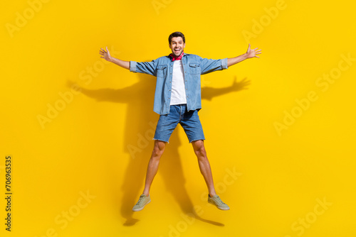 Full size photo of good mood ecstatic guy wear jeans jacket shorts jumping celebrate black friday isolated on yellow color background