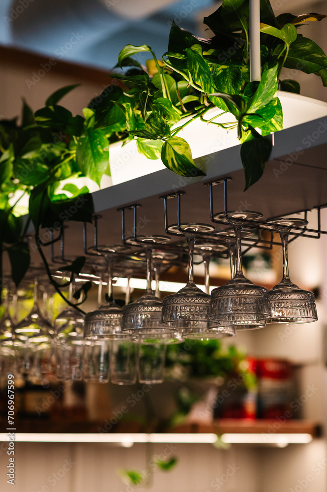 Glasses hang over bar counter. Many glasses hanging from bar rack