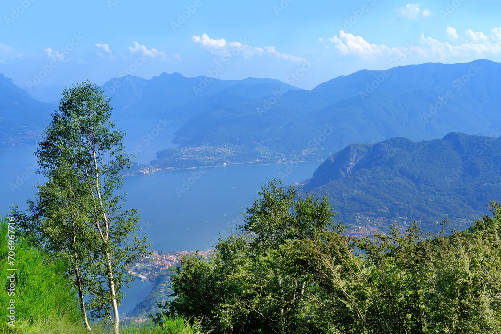 idyllic Mountain Landscape Photography at Lake Como, green hills above Lake Como in Italy, mountains against backdrop of blue sky, concept of tourist season, tourism destination