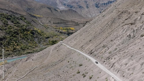 Aerial 4K video by a drone following a 4x4 SUV on the road through the cold desert mountains of Spiti Valley photo