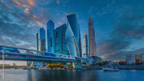 Futuristic Cityscape at Dawn or Dusk with Reflective Water, Modern Skyscrapers, and Pedestrian Bridge