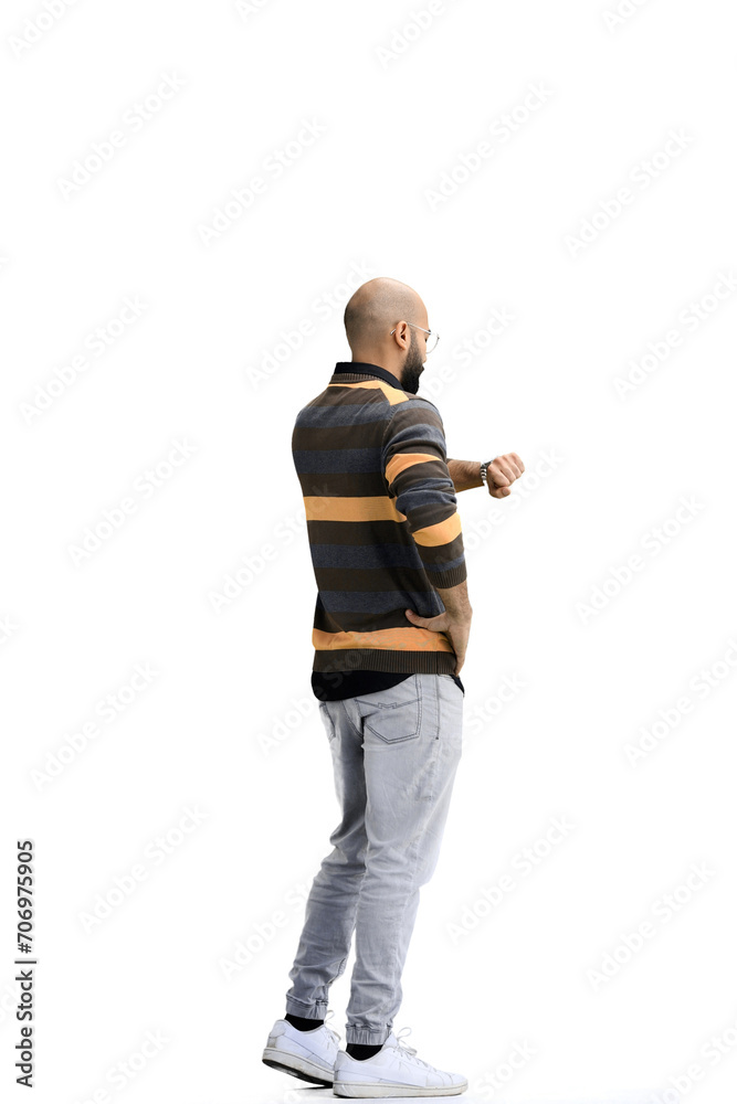 A man, on a white background, in full height, looks at his watch
