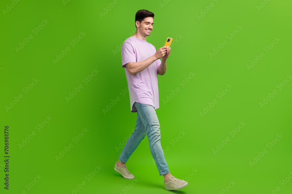 Full length photo of glad nice man freelancer dressed trendy clothes reading instagram facebook post isolated on green color background Full length photo of glad nice man freelancer dressed trendy clothes reading instagram facebook post isolated on green color background
