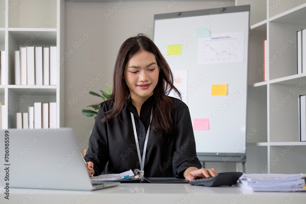 Business woman using calculator and laptop for do math finance on wooden desk in office and business working background, tax, accounting, statistics and analytic research concept