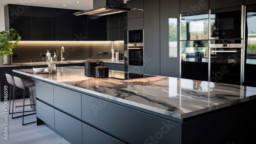 Front view of a modern designer kitchen with smooth handleless cabinets with black edges, black glass appliances, a marble island and marble countertops