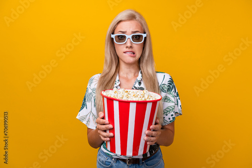 Portrait of excited woman with straight hairstyle in 3d glasses hold popcorn watch thriller bite lips isolated on yellow color background