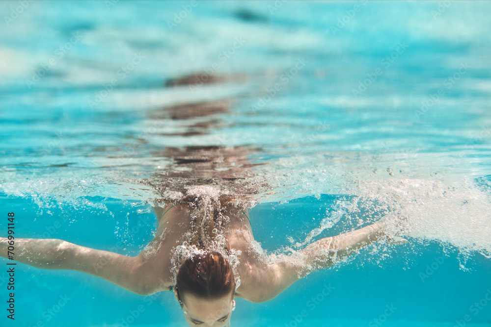 Swimming young woman underwater in pool