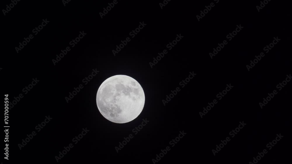 Bright Full Moon In Motion Setting Up in Dark Sky Behind Clouds Bright Full Moon In Motion Setting Up in Dark Sky Behind Clouds