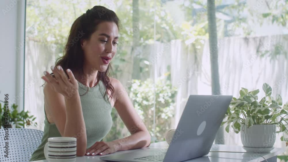 Medium shot of young Caucasian woman using wireless computer while calling someone on video from home Medium shot of young Caucasian woman using wireless computer while calling someone on video from home