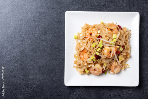Pad Thai with shrimp and vegetables on black slate background. Top view. Copy space