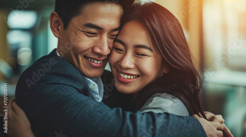 Attractive smiling Asian man hugging woman indoors in the office.