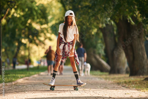 On the road in park. Happy little girl with skateboard outdoors