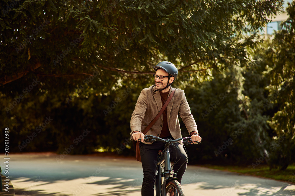 A smiling businessman riding a bicycle to work office with a helmet and glasses on.