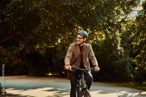 Obraz na płótnie A smiling businessman riding a bicycle to work office with a helmet and glasses on. w salonie