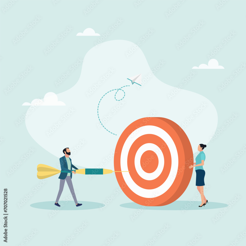An employee tries to throw a dart at a large concentric dart board held by a leader, a concept for motivating employees to achieve goals.
An employee tries to throw a dart at a large concentric dart board held by a leader, a concept for motivating employees to achieve goals.