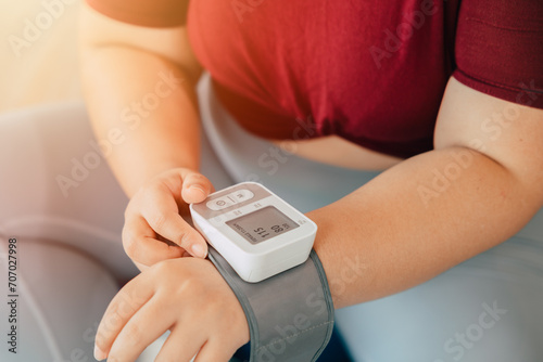 fat women measuring blood pressure using wrist blood vessels monitor modern home medical equipment photo