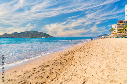 Serene Beach Scene with Mountains  Seagulls  and Resort Buildings