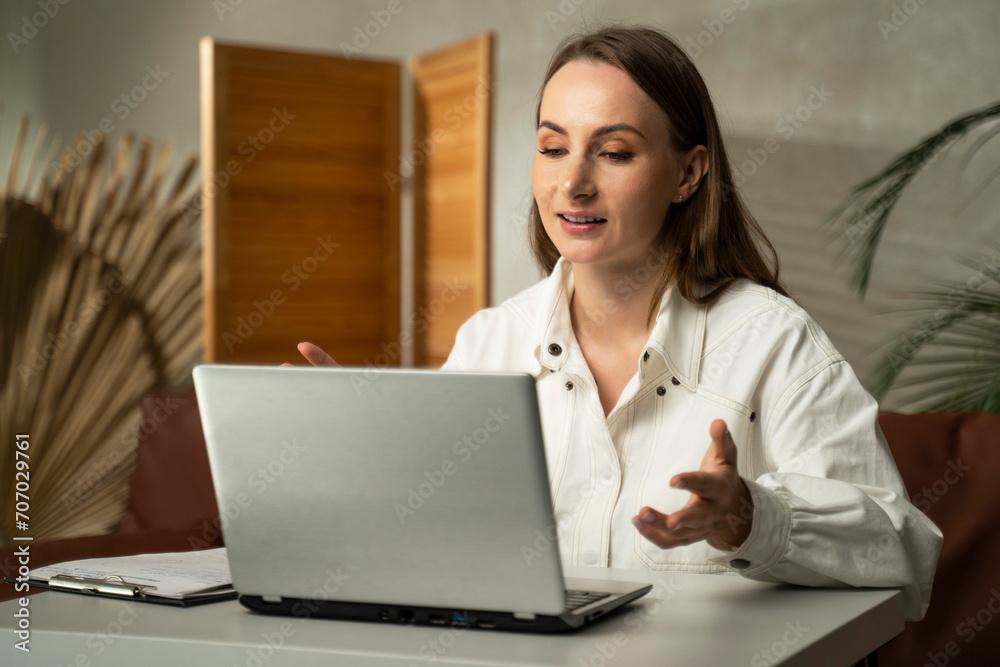 Young woman while working on a laptop at home. Work at home, video conference, video call, online student training course. 