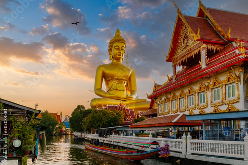 Golden Hour at Thai Temple with Colossal Buddha Statue, Traditional Long-Tail Boat, and Serene River Scene