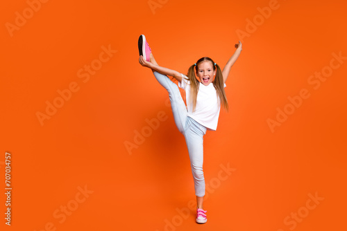 Full length portrait of overjoyed sporty girl hand hold stretch leg empty space isolated on orange color background photo