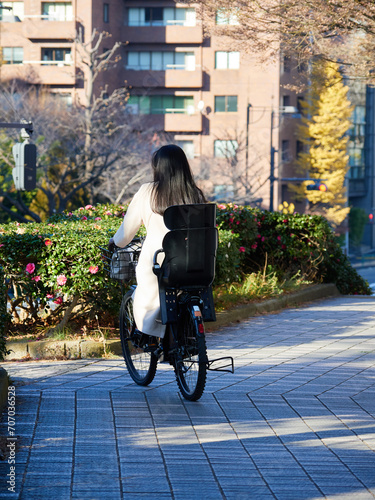 冬の東京都の町でママチャリを乗っている若い女性の後姿