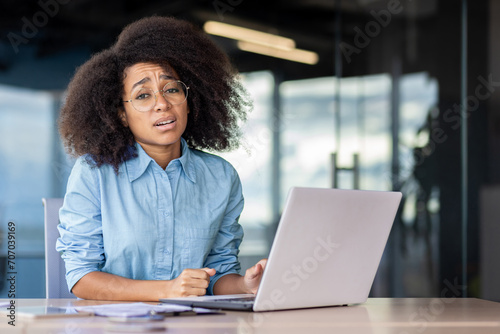 Portrait of dissatisfied disappointed business woman at workplace inside office, office worker sad and unhappy looking at camera, working with laptop, got transaction refusal error. photo
