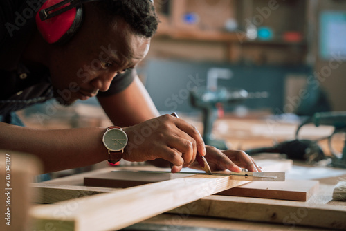 Close up of African male drawing a line on wood for carpentry project 