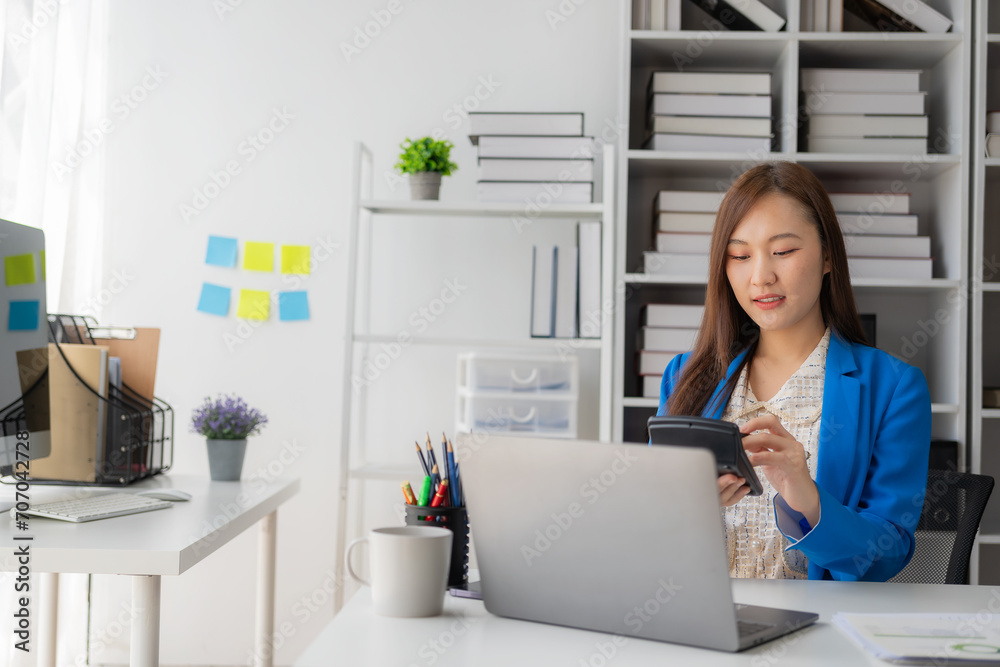 Working with finance and calculator in bank office, Asian female accountant working with laptop and financial documents in office Working with finance and calculator in bank office, Asian female accountant working with laptop and financial documents in office