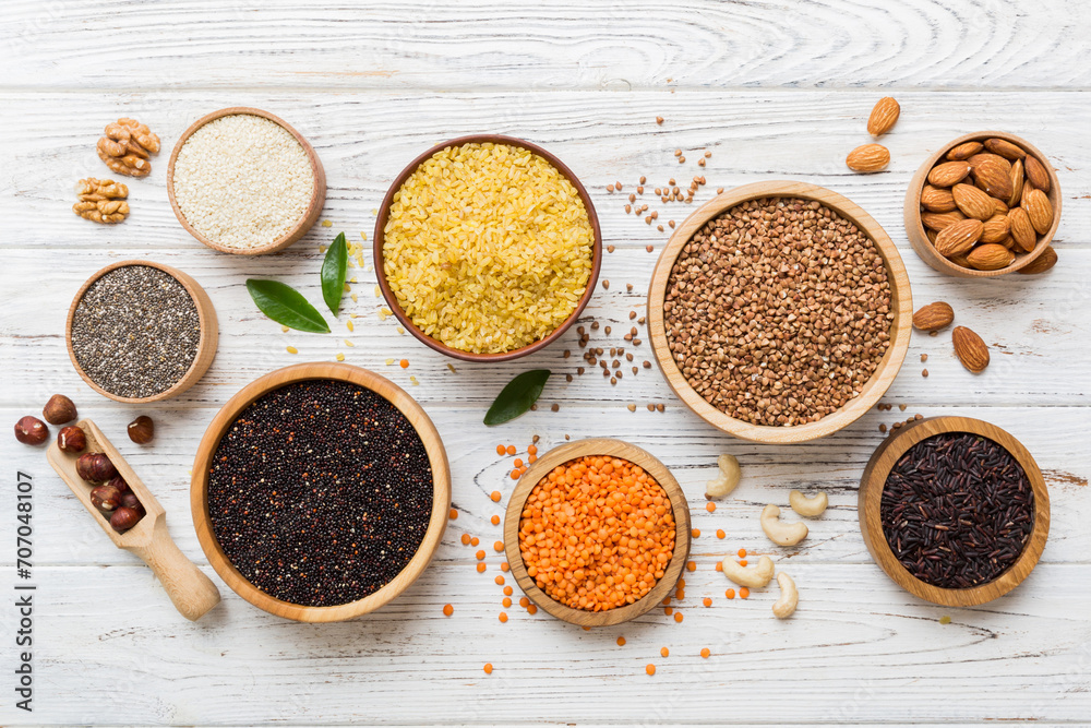 Various superfoods in smal bowl on colored background. Superfood as rice, chia, quinoa, lentils, nuts, sesame seeds, almonds. top view copy space - obrazy, fototapety, plakaty 