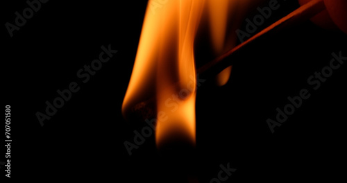 Hand Lights Paraffin Candle using a Match, Black Background. Bright flame, fire, ignition in a dark room