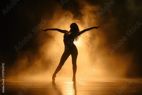 Silhouette of a dancer against a bright stage light