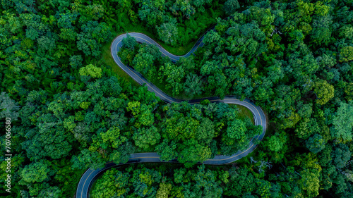 Aerial top view road in forest with car motion blur. Winding road through the forest. Car drive on the road between green forest. Ecosystem ecology healthy environment road trip. © Darunrat