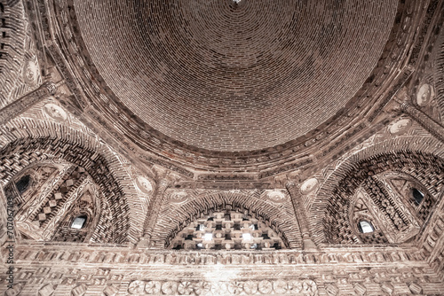 Dome and sophisticated wall decorations of raw bricks. Interior of Samanid Mausoleum, medieval masterpiece (IX-X c. AD). Monochrome. April 18, 2023. Bukhara, Uzbekistan photo