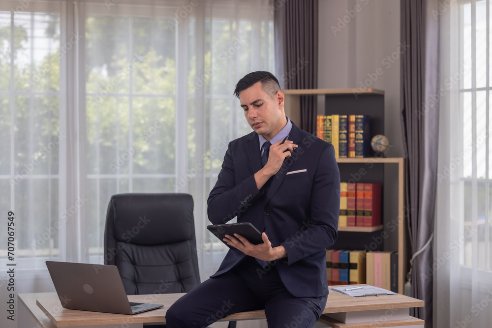 Male manager in suit multitask on laptop, tablet in modern office, talk to clients, analyze project Male manager in suit multitask on laptop, tablet in modern office, talk to clients, analyze project